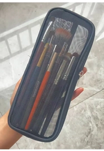 Detail of black mesh storage bag containing multiple colorful makeup brushes with zippers