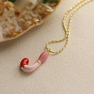 Gros plan d'un collier doré avec pendentif en forme de J rose brillant et détail rouge