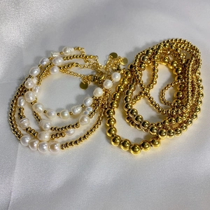 Close-up of golden steel beads and natural freshwater pearls on a white silk background
