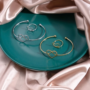Close-up of heart-shaped open bracelets and matching rings in gold and silver finish
