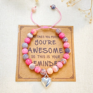 Détail du bracelet en perles réglable avec pendentif cœur sur carte cadeau en kraft