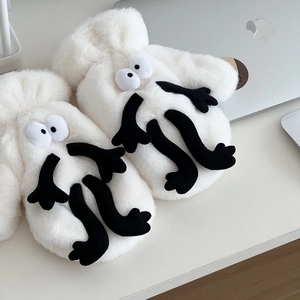 Detail showing plush white monster gloves with large eyes on a desk workspace