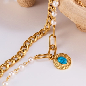 Macro detail of gold layered bracelet with white pearl and turquoise charm pendant