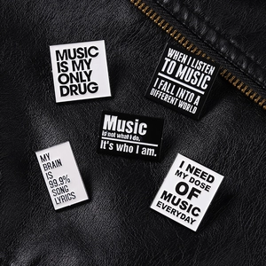Detail view of five black and white enamel music badges on a black leather jacket