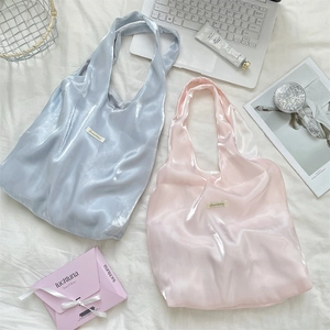 Close-up of light blue and pink satin tote bags with glossy finish and brand label