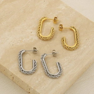 Detailed view of U-shaped twisted cable earrings in gold and silver on a stone display