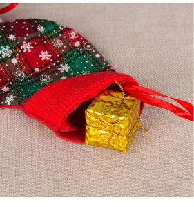 Close-up of fabric Christmas stocking with red-green plaid and golden gift box detail