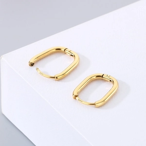Pair of minimalist golden stainless steel U-shaped hoop earrings on geometric background