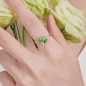 Primer plano de anillo con esmeralda cuadrada y banda de plata trenzada en mano
