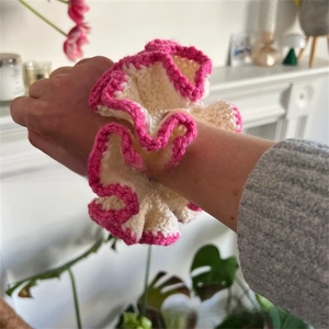 Close-up of handmade crochet scrunchie in beige and pink worn on a wrist
