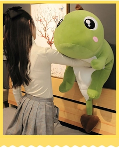 Girl hugging a large green dinosaur plush pillow with a heart tail in a cozy bedroom