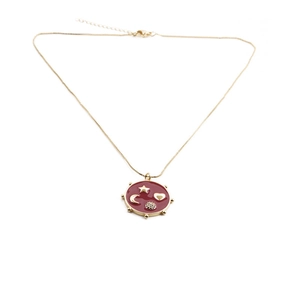 Detailed shot of gold necklace with red enamel pendant featuring star, moon, and heart charms