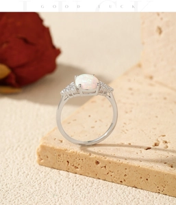 Macro shot of silver ring featuring oval white opal and sparkling side diamonds