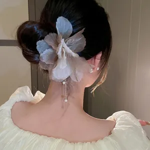 Épingle à cheveux fleur en tulle avec perles et glands dorés sur une coiffure en chignon