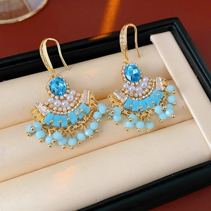 Vue détaillée de boucles d'oreilles en forme d'éventail avec perles et pierres bleues