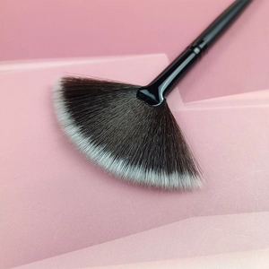 Dettaglio pennello a ventaglio con setole sfumate bianco e nero su sfondo rosa
