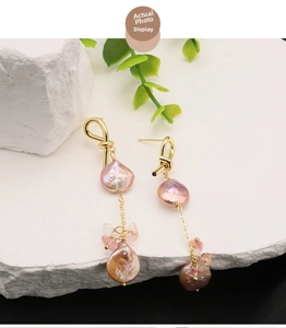 Detail of baroque pink pearl earrings with 18k gold chain on natural stone background