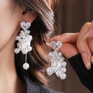 Detail of heart-shaped zircon earrings with elegant pearl fringe and long tassel design