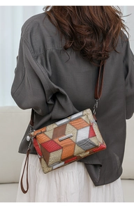 Detail of color-block crossbody bag featuring mixed textures and silver logo plaque