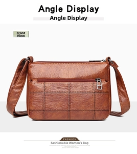 Detailed front view of brown leather crossbody bag with plaid stitching and zip pocket