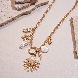 Detailed macro view of golden sun, seashell, and pearl pendants on layered chain