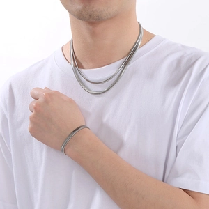 Model wearing silver flat snake chain necklace and matching open cuff bracelet set