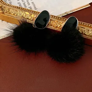 Elegant twisted oval earrings with black enamel drop and cozy faux fur pompom accents