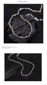 Detailed close-up showing silver fleur-de-lis and cross links of the necklace
