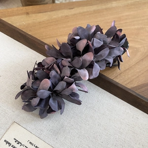 Detailed view of dark purple fabric floral hair clip with elegant resin claw on wood