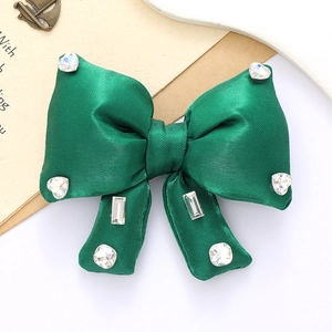 Macro shot of emerald green satin bow accessory with sparkling rhinestone embellishments