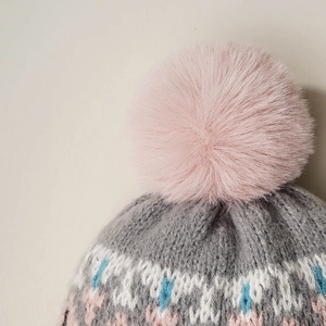 Winter knit beanie with gray geometric patterns and a large fluffy pink faux fur pom-pom top