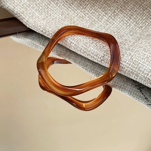 Macro shot of amber acrylic wave bracelet with irregular texture and mirror reflection