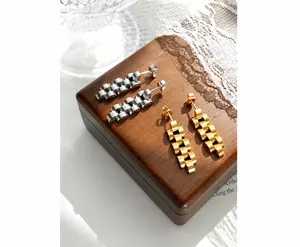 Nahaufnahme von gold- und silbernen Ohrringen im Gliederarmband-Stil auf Vintage-Holzgrund