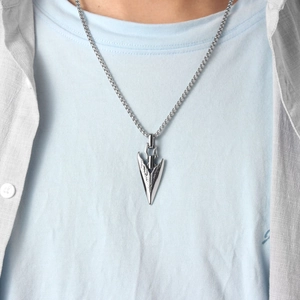 Close-up of vintage silver arrowhead pendant with box chain on a male model