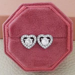 Detail of silver heart-shaped stud earrings with zircons in a pink velvet box
