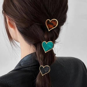 Detail view of heart-shaped hair clips in tortoiseshell and marble patterns on a ponytail