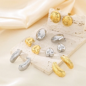Detailed view of geometric gold and silver stud earrings on a minimalist stone tray