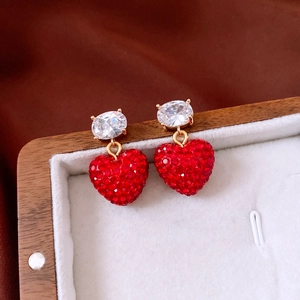 Gros plan de boucles d'oreilles cœur étincelantes avec cristaux rouges et dorures