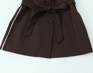 Detail view of coffee brown trousers featuring white side stripes and matching fabric belt
