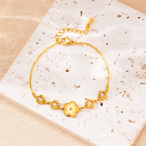 Macro detail of gold-plated flower and star charm bracelet with sparkling zircon stones