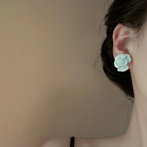 Detail showing a light blue layered flower earring worn by a model for a summer look