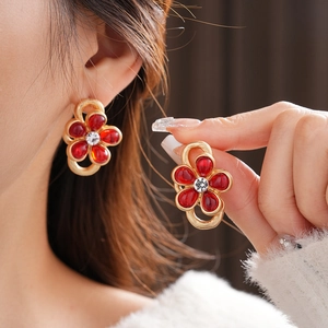 Close-up of vintage flower earrings with red petals, golden rim and center rhinestone