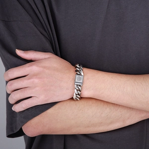 Macro detail of men's silver Cuban link bracelet with iced-out pave diamond plaque