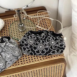 Detailed embroidery and pearl drawstring closure on elegant black floral makeup bags