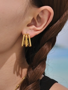 Detailed close-up of triple-layered gold hoop earrings with textured and polished finishes