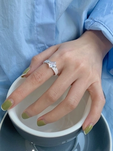 Close-up of minimalist 925 silver ring with square zircon on finger holding a white cup