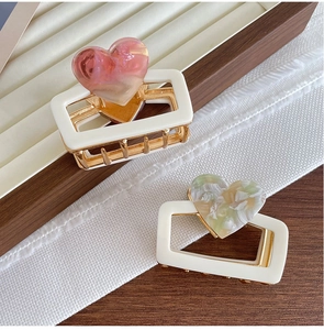 Detail view of heart-shaped hair claws with resin hearts and gold metal teeth