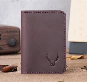 Macro shot of dark red crazy horse leather card holder with embossed bull logo on wood