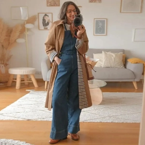 Detail eines braunen Trenchcoats und einer Denim-Latzhose im Spiegel-Selfie