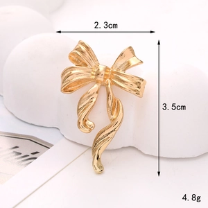 Detail view of a 2.3cm by 3.5cm gold bow accessory with precise size measurements